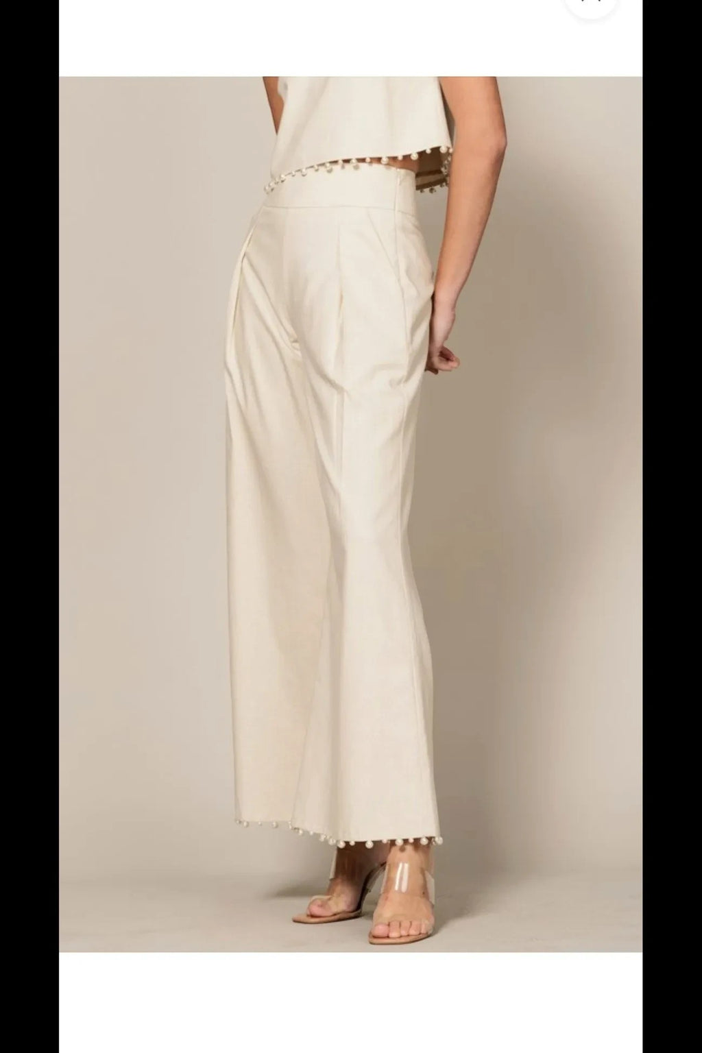 Shadow & Shine cream sleeveless crop top and high-waisted wide-leg trouser set with playful pom-pom trim details.