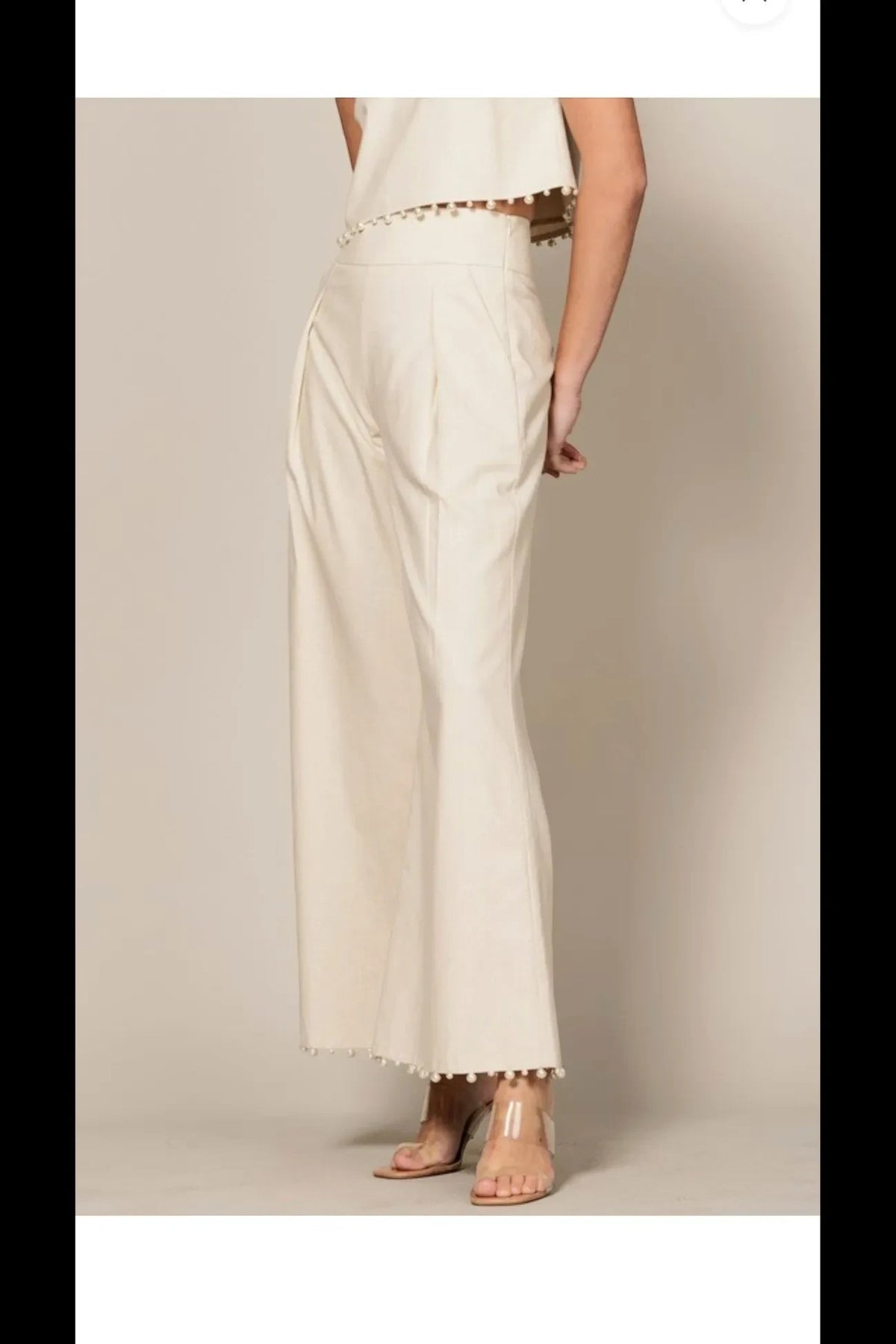 Shadow & Shine cream sleeveless crop top and high-waisted wide-leg trouser set with playful pom-pom trim details.