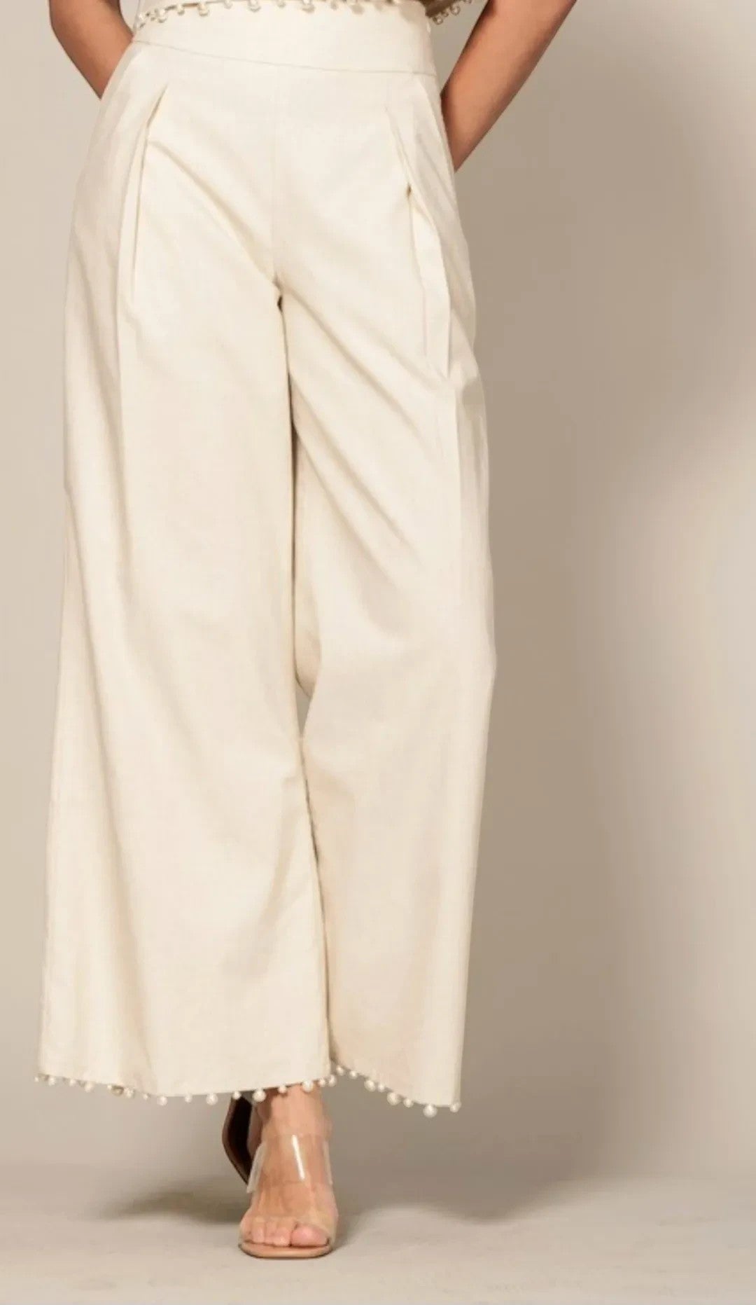 Shadow & Shine cream sleeveless crop top and wide-leg trouser set with delicate pom-pom trim hem detail.